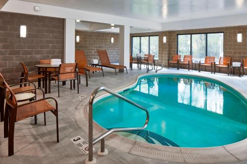 una piscina en una habitación de hotel con mesas y sillas en Fairfield Inn & Suites by Marriott Albany Airport en Albany