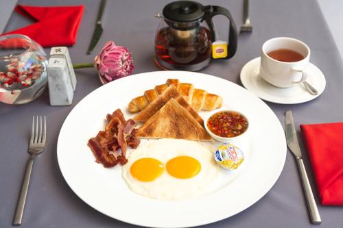 ein Teller mit Frühstücksessen mit Eiern, Speck und Toast in der Unterkunft Bopha Watbo Residence in Siem Reap