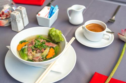 eine Schüssel Suppe und eine Tasse Kaffee auf dem Tisch in der Unterkunft Bopha Watbo Residence in Siem Reap