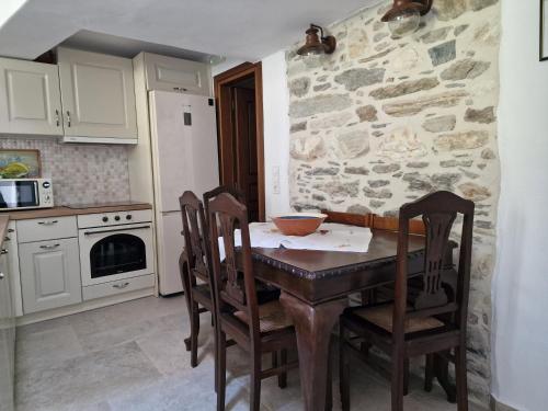 a kitchen with a table and chairs and a stone wall at PYRGOS - Traditional house at Kaloxilos, Naxos in Khalkíon