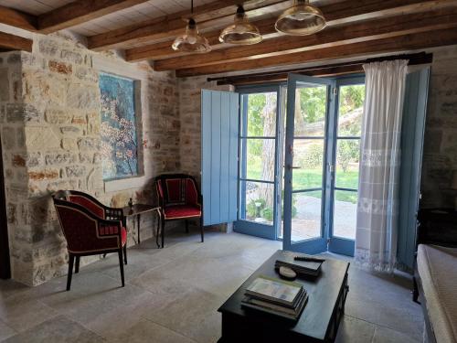 a living room with a table and chairs and windows at PYRGOS - Traditional house at Kaloxilos, Naxos in Khalkíon