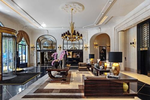 パリにあるプリンスドガル ア ラグジュアリーコレクションホテル パリのシャンデリアとソファ付きの広いリビングルーム