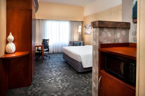 a hotel room with a bed and a microwave at Courtyard by Marriott Kansas City Shawnee in Shawnee