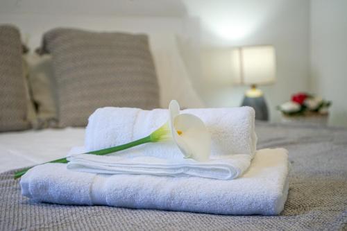 a pile of towels and a flower on a bed at Oásis Fonte Grande in Santo António