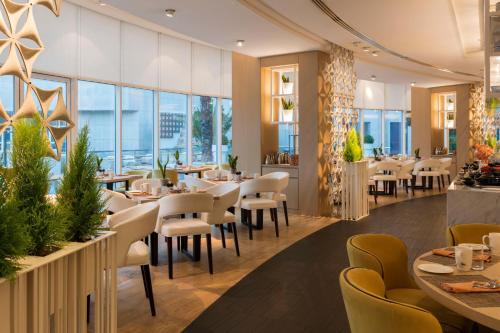 a restaurant with tables and chairs and large windows at Le Royal Meridien Abu Dhabi in Abu Dhabi