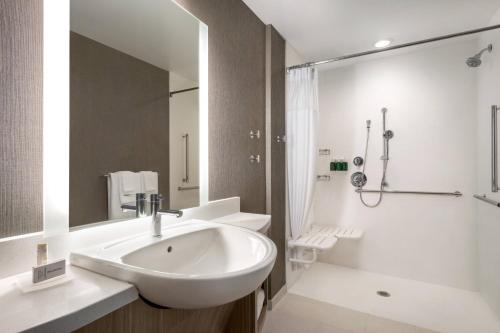SpringHill Suites by Marriott Milwaukee West/Wauwatosa في اوواتوسا: حمام أبيض مع حوض ودش