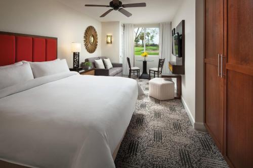 a bedroom with a large white bed and a living room at Marriott's Shadow Ridge II - The Enclaves in Palm Desert