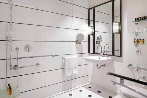 bagno bianco con lavandino e specchio di Cotton House Hotel, Autograph Collection a Barcellona