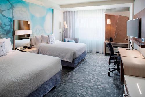 a hotel room with two beds and a desk at Courtyard by Marriott Dallas Carrollton and Carrollton Conference Center in Carrollton
