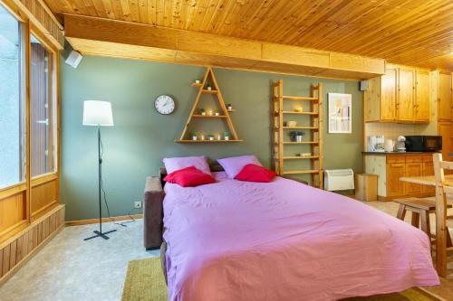 une chambre avec un grand lit avec des oreillers rouges dans l'établissement Le Petit Sapin, à La Bresse