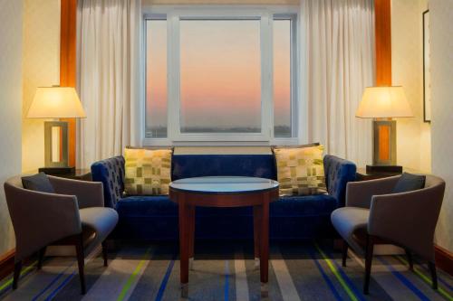 a living room with a couch and a table and a window at Sheraton Brussels Airport Hotel in Zaventem