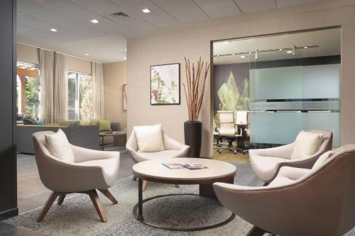 a living room with chairs and a table and a piano at Courtyard by Marriott Nashville SE/Murfreesboro in Murfreesboro