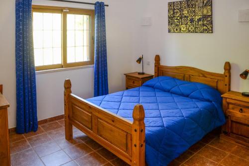 - une chambre avec un lit doté de draps bleus et une fenêtre dans l'établissement Casa Rina, à Lagoa