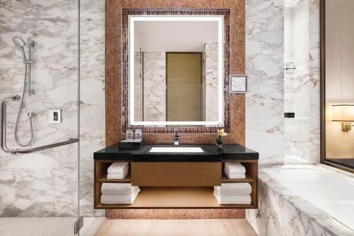 a bathroom with a sink and a tub and a mirror at Sheraton Beijing Lize Hotel in Beijing