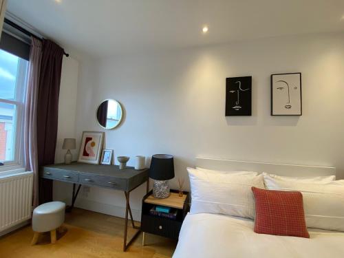 a bedroom with a bed and a desk with a mirror at New stylish Fulham apartment - 2 bed in London