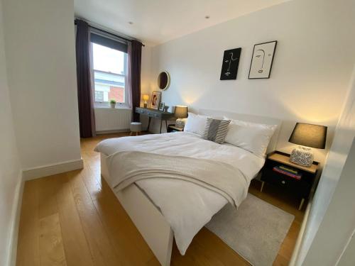 Un dormitorio con una gran cama blanca y una ventana en New stylish Fulham apartment - 2 bed, en Londres