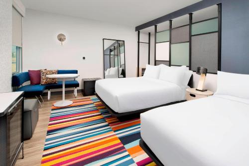 ウィルミントンにあるAloft Wilmington at Coastline Centerのベッド2台とカラフルなラグが備わるホテルルームです。