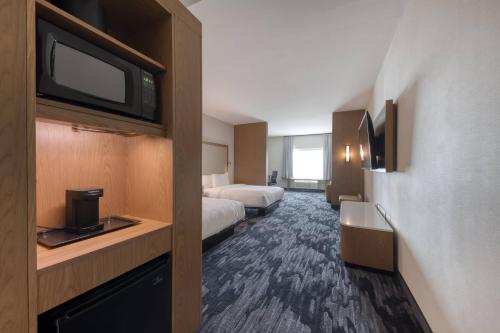 a hotel room with two beds and a flat screen tv at Fairfield Inn & Suites by Marriott Charlotte Belmont in Belmont