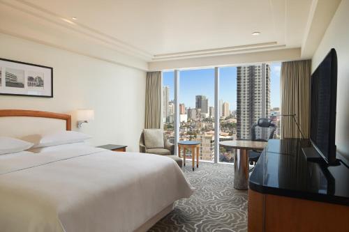 a hotel room with a bed and a large window at Sheraton Manila Bay in Manila