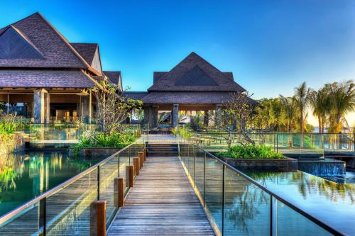 einen Holzsteg, der zu einem Haus mit einem Teich führt in der Unterkunft The Westin Turtle Bay Resort & Spa, Mauritius in Balaclava