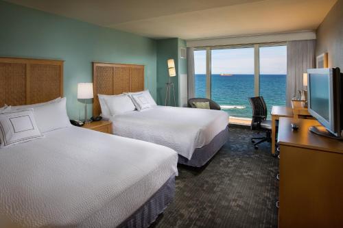 a hotel room with two beds and a view of the ocean at Courtyard by Marriott Fort Lauderdale Beach in Fort Lauderdale