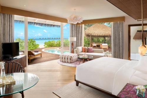 a bedroom with a bed and a living room at JW Marriott Maldives Resort & Spa in Funadhoo