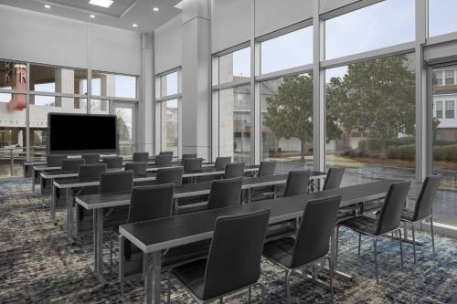 a conference room with tables and chairs and a flat screen tv at AC Hotel by Marriott Charlotte Ballantyne in Charlotte