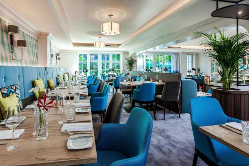 a dining room with tables and blue chairs at Courtyard by Marriott Hamburg Airport in Hamburg