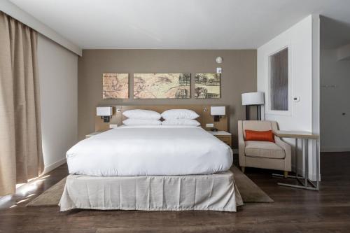 a bedroom with a large white bed and a chair at Delta Hotels by Marriott Raleigh-Durham at Research Triangle Park in Durham