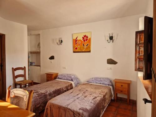 1 dormitorio con 2 camas y una foto en la pared en Casa El Banco, en Iznate