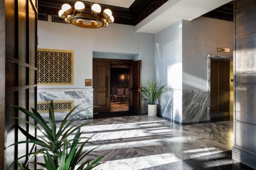 a lobby with a potted plant and a chandelier at The Barfield, Autograph Collection in Amarillo