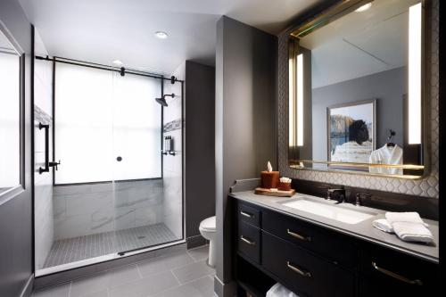 a bathroom with a shower and a sink and a mirror at The Barfield, Autograph Collection in Amarillo