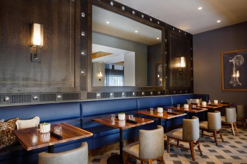 a restaurant with wooden tables and a large mirror at The Barfield, Autograph Collection in Amarillo