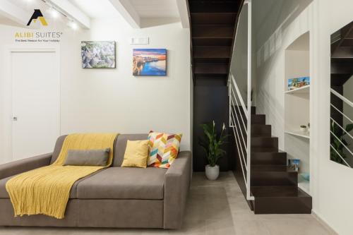 a living room with a couch and a staircase at ALIBI SUITES Loft: Centralissimo con Free WiFi, Netflix, A/C e tutti i Comfort in Ruvo di Puglia