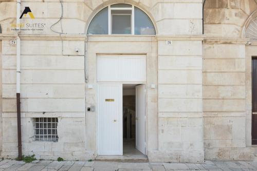 a white building with a white door and two windows at ALIBI SUITES Loft: Centralissimo con Free WiFi, Netflix, A/C e tutti i Comfort in Ruvo di Puglia