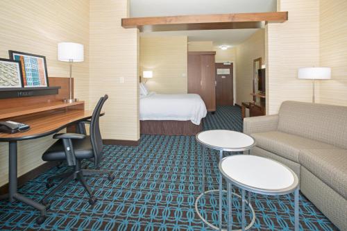 Fairfield Inn & Suites by Marriott Burlington في برلينغتون: غرفة في الفندق مع أريكة ومكتب وسرير