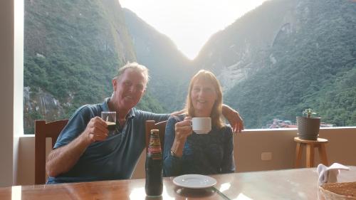 Un uomo e una donna seduti a un tavolo a bere caffè di Picos House a Machu Picchu
