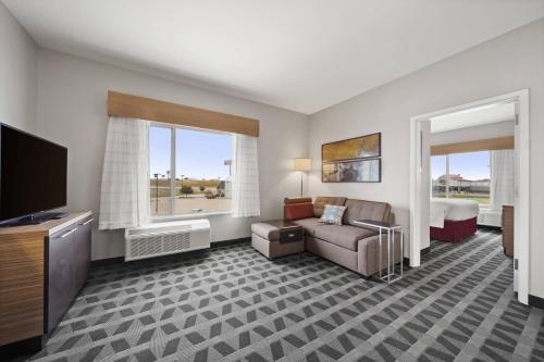 TownePlace Suites Waco Northeast في واكو: غرفه فندقيه فيها اريكه وسرير وتلفزيون