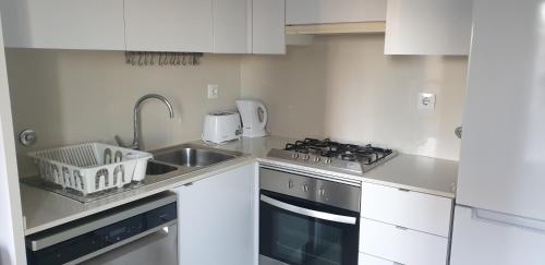 a white kitchen with a sink and a stove at Free parking & 5min walk to Subway in Lisbon