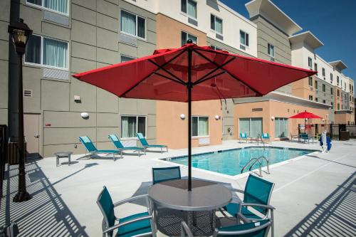 un tavolo con ombrellone rosso accanto a una piscina di TownePlace Suites by Marriott Goldsboro a Goldsboro