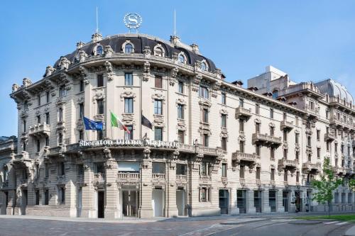ein großes weißes Gebäude mit Flaggen darüber in der Unterkunft Sheraton Diana Majestic in Mailand
