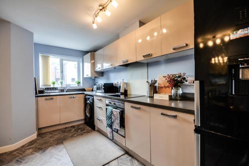 a kitchen with white cabinets and a black refrigerator at Three Bedroom House in Runcorn Close To The Lake with Parking in Runcorn
