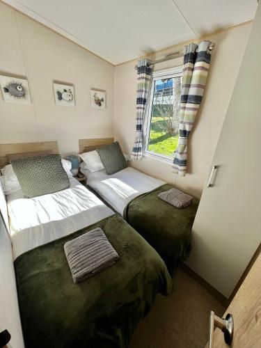 two beds in a small room with a window at Newquay Bay Resort - SummerBreeze PV54 in Newquay Bay Resort