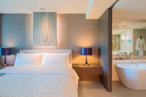 a hotel room with a bed and a bath tub at Le Meridien Suvarnabhumi, Bangkok Golf Resort and Spa in Bangna