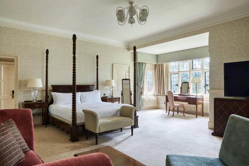 a bedroom with a bed and a living room at Hanbury Manor Marriott Hotel & Country Club in Ware