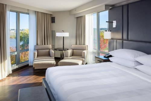 um quarto com uma cama, 2 cadeiras e janelas em South Sioux City Marriott Riverfront em South Sioux City