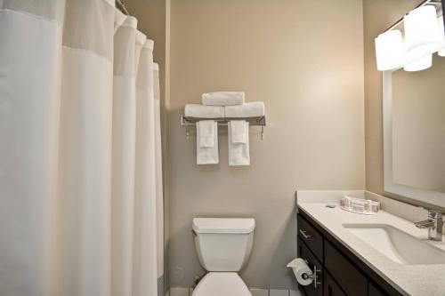a bathroom with a toilet and a sink and a mirror at TownePlace Suites Sioux Falls in Sioux Falls