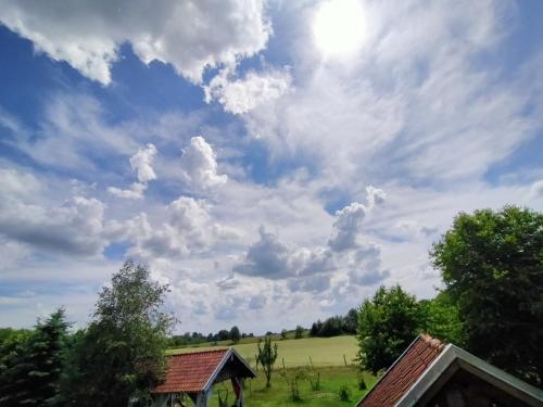 a cloudy sky above a field and a house at Apartamenty na wsi Horses&Relax in Młynary