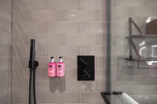 a shower with two pink shampoo bottles in a bathroom at Moxy NYC Downtown in New York