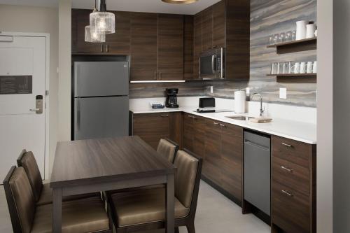 a kitchen with a table and a refrigerator and cabinets at Residence Inn by Marriott Jacksonville Downtown in Jacksonville